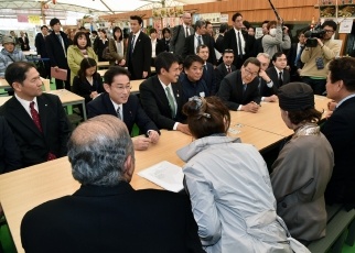 Minister Kishida sits around a desk being briefed on the damage and recovery from the Kumamoto earthquake