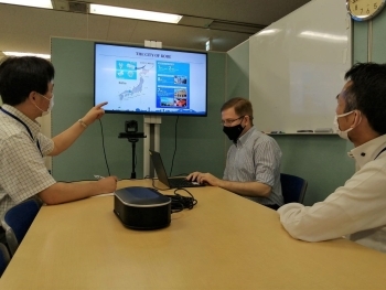 (Photo9) Mr. Leo Luchuk operating a computer and two men staring at the monitor