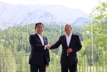 Two leaders who shake hands with each other facing straight at the camera with a smile