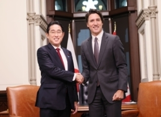 Two leaders who shake hands with a smile facing straight at a camera