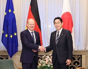 Two leaders who shake hands with a smile facing straight at a camera