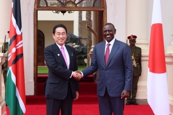 Two leaders who shake hands with a smile facing straight at a camera