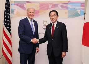 Two leaders who shake hands with a smile facing straight at a camera