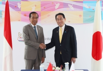 Two leaders who shake hands with a smile facing straight at a camera
