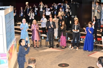 A singer AI who sings a song a cappella and the G7 leaders' spouses who clap their hands