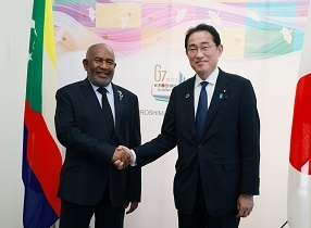 Two leaders who shake hands with a smile facing straight at a camera