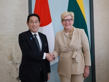 Two leaders who shake hands with a smile facing straight at a camera