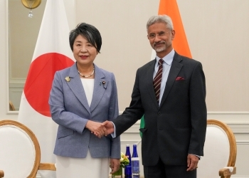 Two Ministers shake hands facing straight at a camera