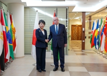 Two Ministers who shake hands facing straight at a camera
