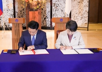 Two Ministers who sign the note after having a seat at a table