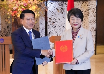 Two Ministers who shake hands facing straight at a camera after exchanging signed notes