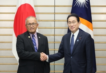 Two leaders who shake hands with a smile facing straight at a camera