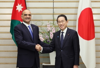 Two leaders who shake hands with a smile facing straight at a camera