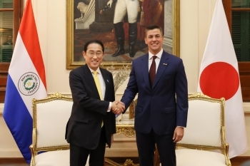 Two leaders who shake hands with a smile facing straight at a camera