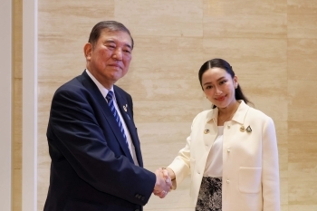 Two leaders who shake hands with a smile facing straight at a camera