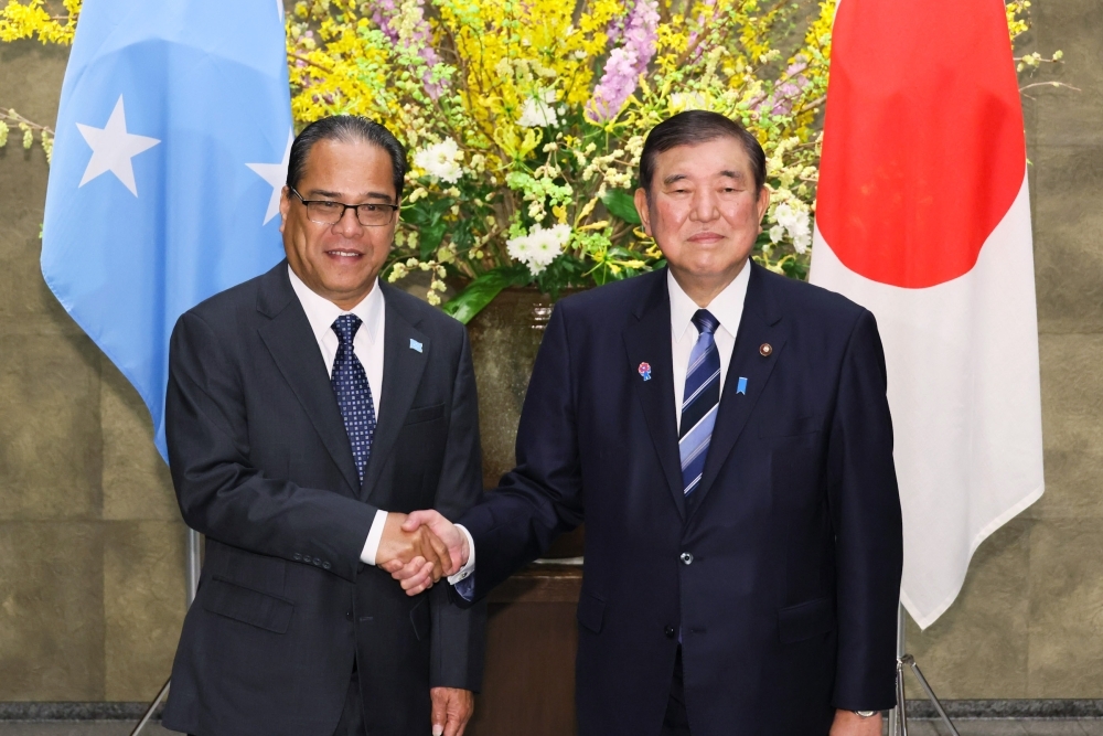 Two leaders who shake hands with a smile facing straight at a camera