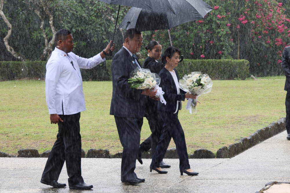 Prime Minister Ishiba and his wife carry flowers in the rain to the Cenotaph to the Fallen Japanese in Caliraya, Laguna