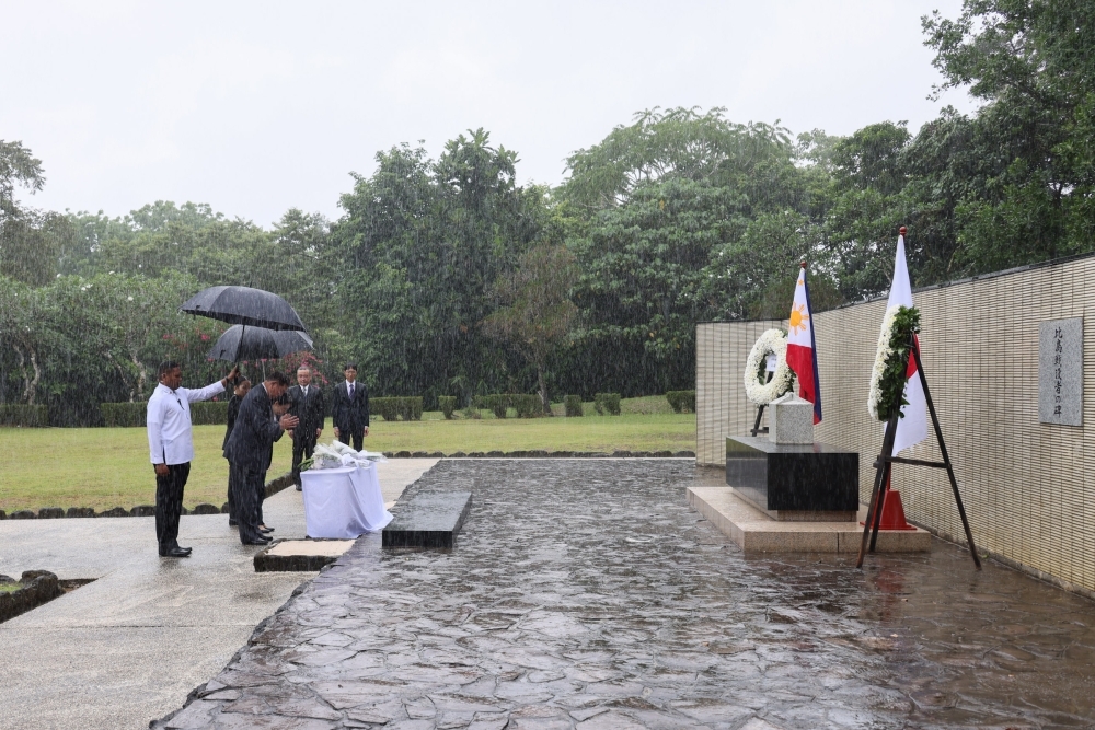 Prime Minister Ishiba and Mrs. Ishiba facing the monument while raining