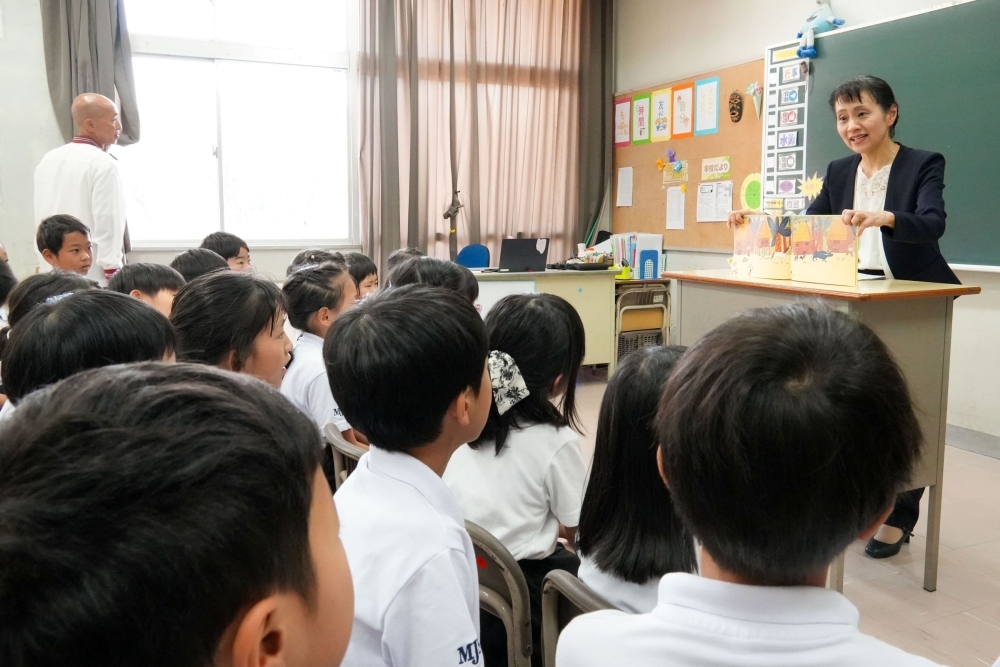 Mrs. ISHIBA reading a picture book to the students at a classroom