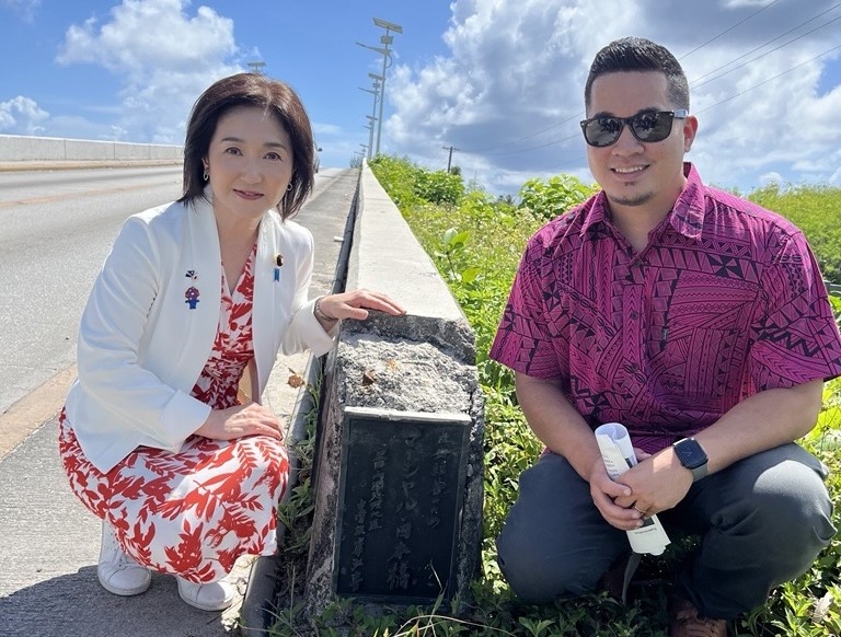 Parliamentary Vice- Minister Ikuina in front of the Majuro Bridge memorial plate that says 'Marshall - Nihonbashi for friendship and goodwill'