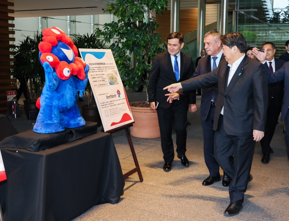Chief Cabinet Secretary HAYASHI Chief Cabinet Secretary Hayashi is explaining the Expo board to Speaker Mr. ISMOILOV, next to the Expo next to the character “Myakumyaku”