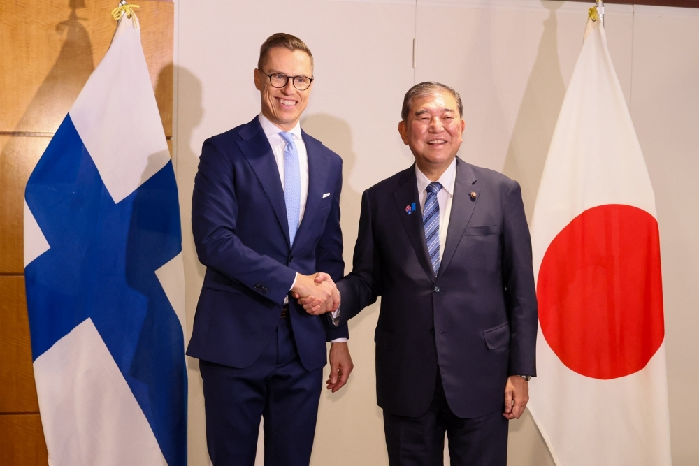 Prime Minister Ishiba shaking hands with President STUBB in front of the national flags