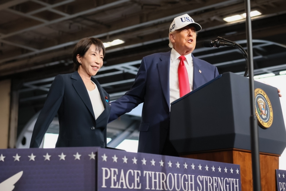 President Trump introducing Prime Minister Takaichi to the members of the U.S. forces on the podium