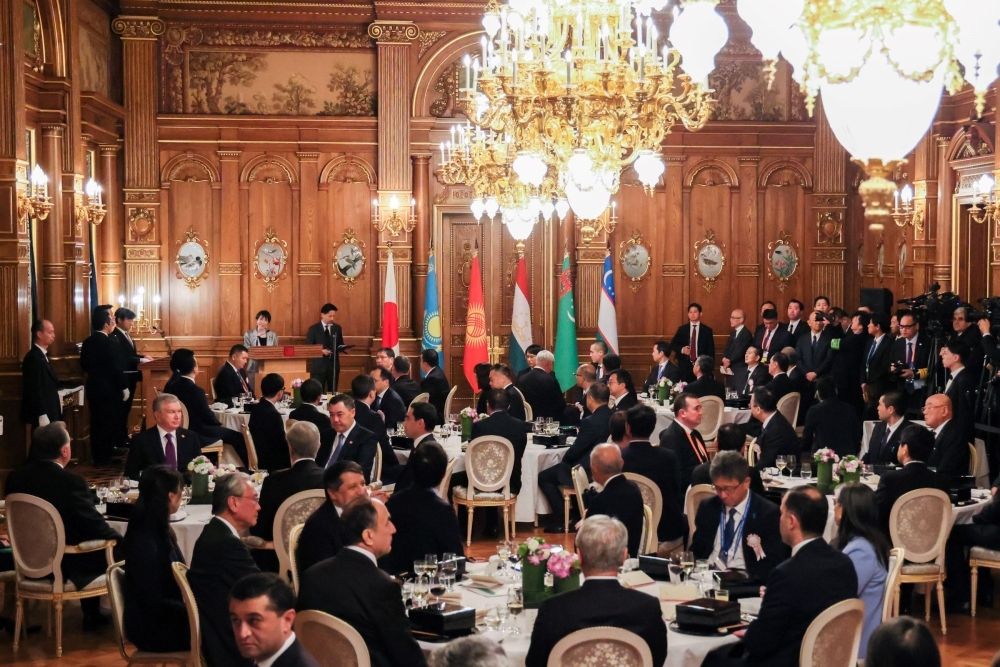 Prime Minister Takaichi delivering a speech at the banquet and the attendees listening in the hall