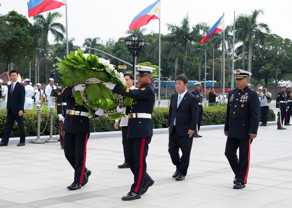 Minister Motegi walking after the soldiers carrying the flower