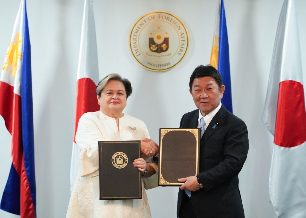 Both Foreign Minister MOTEGI and Hon. Maria Theresa Lazaro, Secretary of Foreign Affairs, holding signed documents and shaking hands