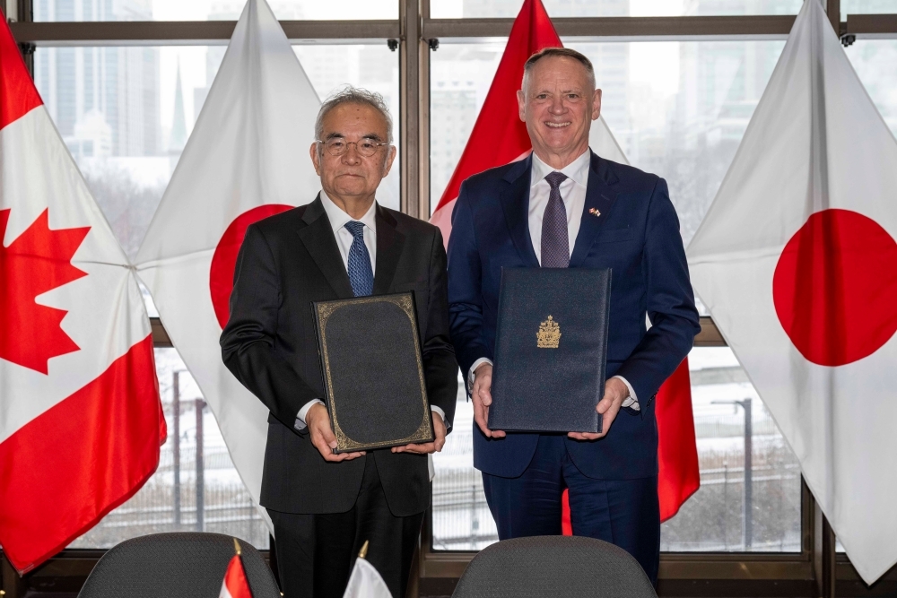 Both Ambassador YAMANOUCHI and Minister McGuinty holding documents and posing for a photograph