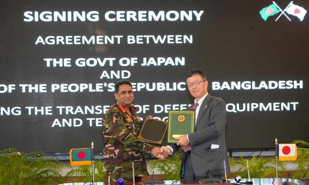 Representatives of the Japanese government and the Bangladesh government exchanging signed documents and shaking hands