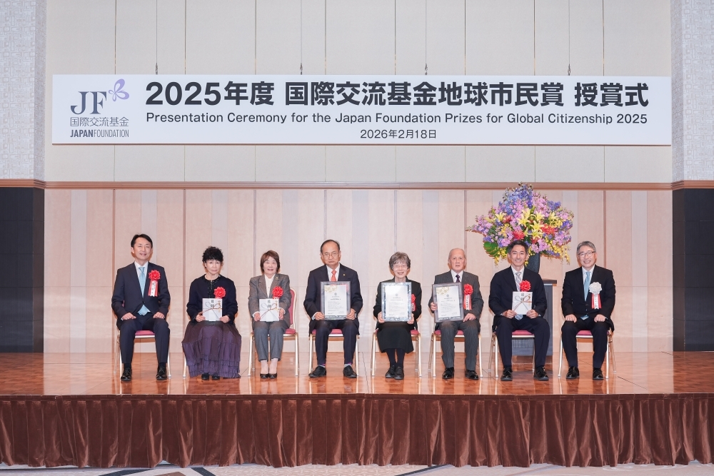 The scene of the award winners seated in a row on chairs on stage