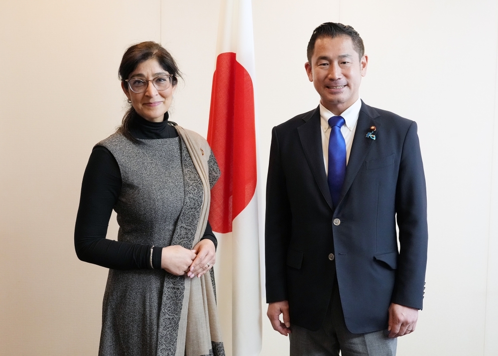 Parliamentary Vice-Minister Onishi and Director Holla Maini standing in front of the Japanese flag