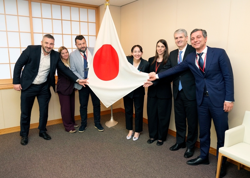 Commemorative photo of Parliamentary Vice-Minister Eri, and the government officials from the Balkan region, holding the Japanese flag