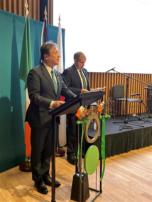 A close-up photo of State Minister HORII delivering remarks on behalf of the Government of Japan