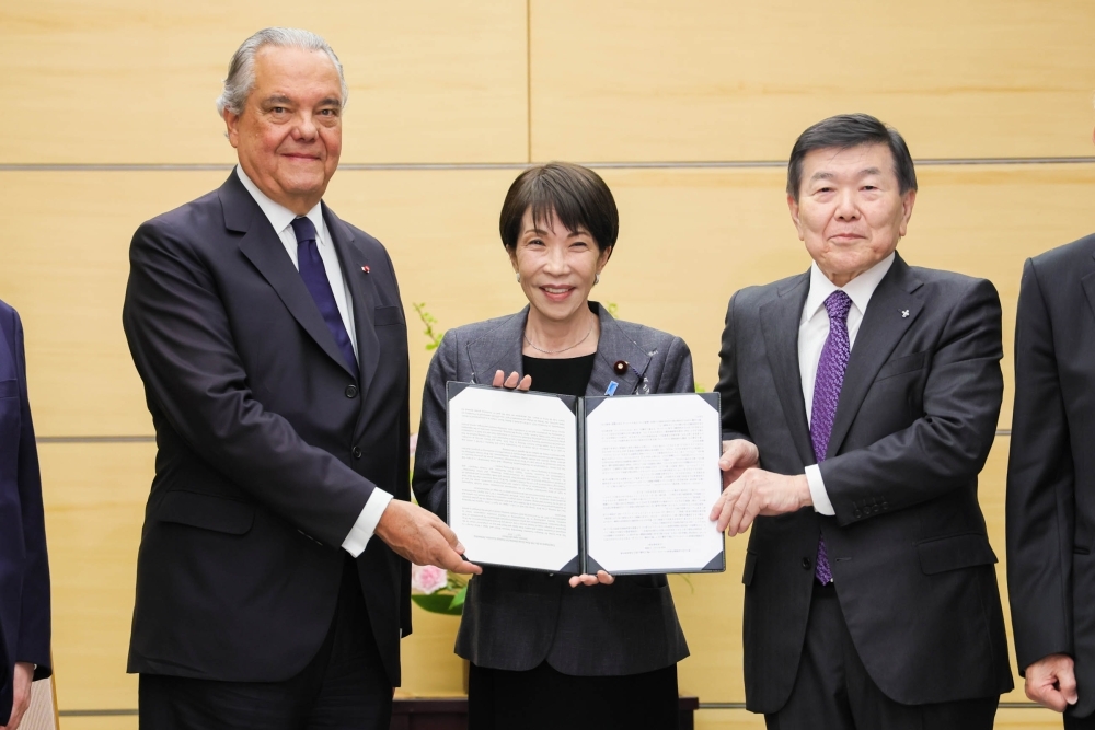 Prime Minister Takaichi holding the Final Report with the chairs of the meeting 