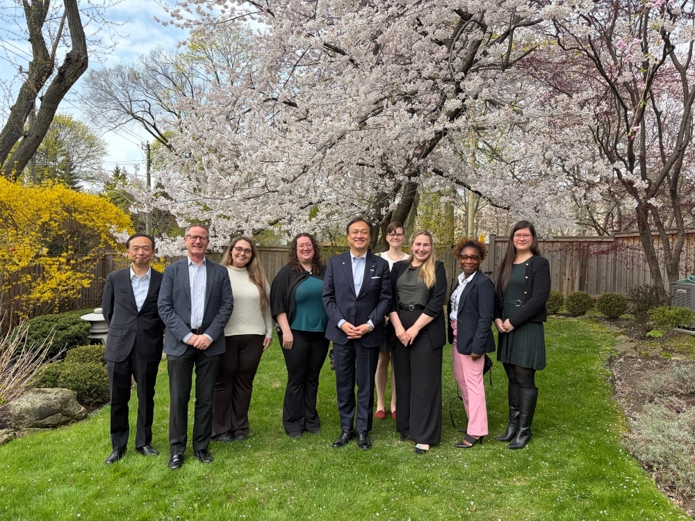 Commemorative photo taken in front of a cherry tree featuring State Minister Horii and Former JET Programme Participants