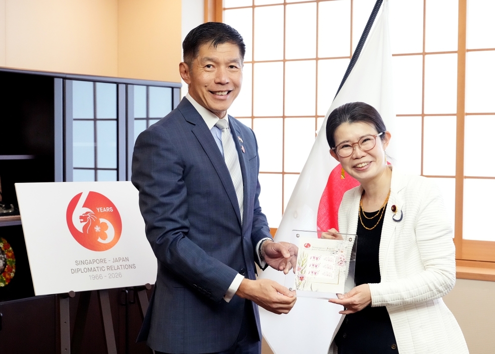 Two shot of State Minister KUNIMITSU and H.E. Mr. ONG, Ambassador of Singapore to Japana, with a commemorative stamp in between
