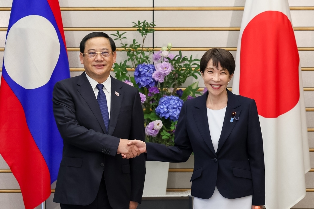 Prime Minister Takaichi shaking hands with Prime Minister Sonexay in front of national flags of two countries