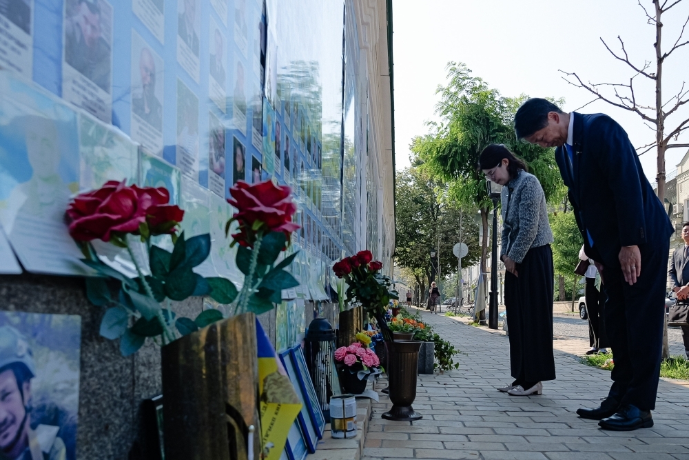 State Minister Kunimitsu praying in front of the wall of remembrance