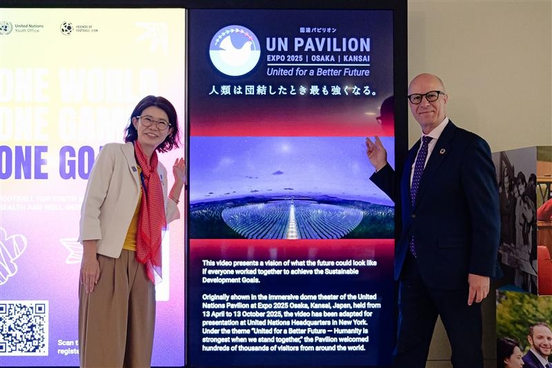 State Minister KUNIMITSU taking a commemorative photo in front of the UN Pavilion panel