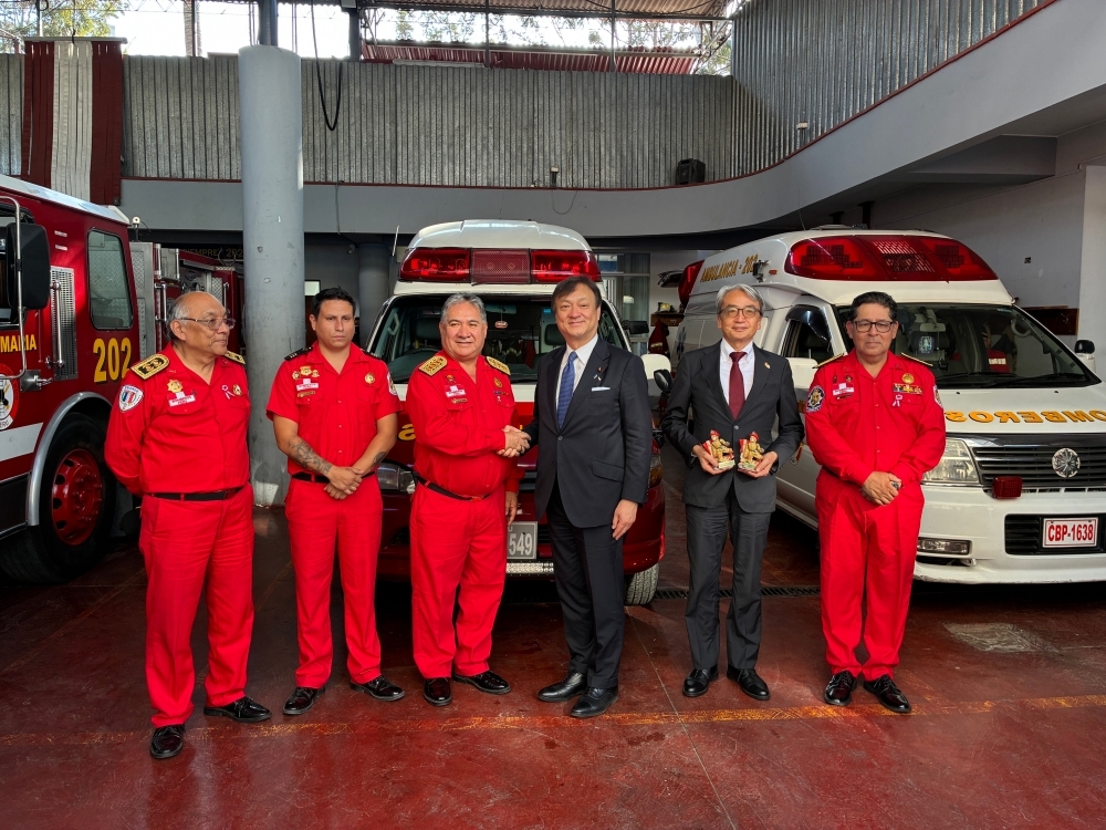 State Minister HORII taking a photo with fire brigade personnel in front of ambulances