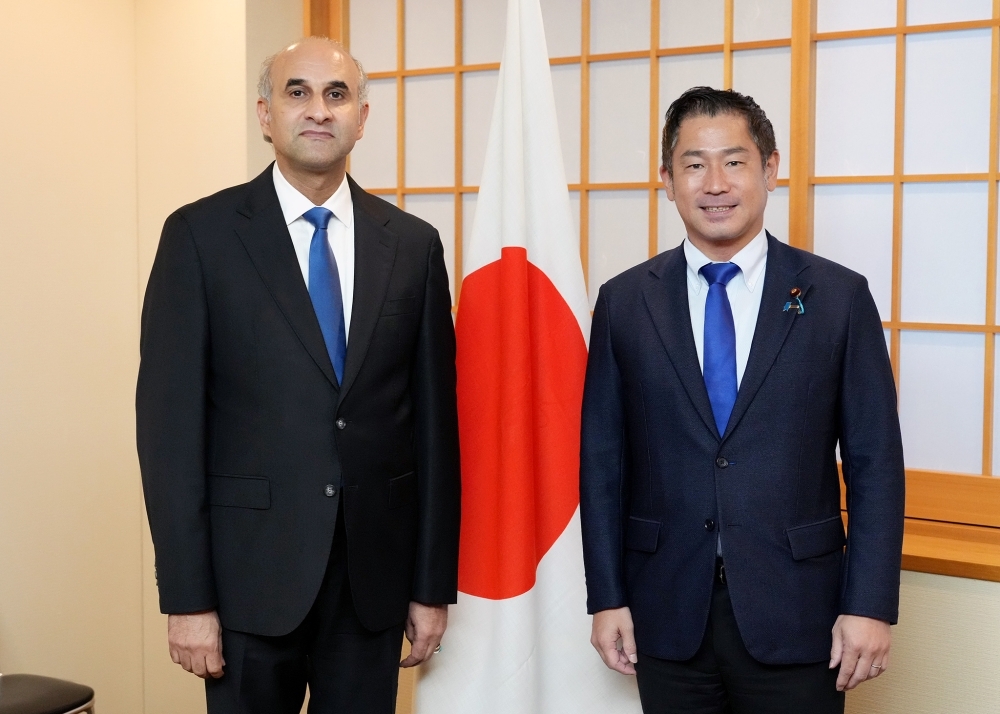Parliamentary Vice-Minister ONISHI taking a picture with Chargé d'Affaires Alnaas in front of Japanese national flag