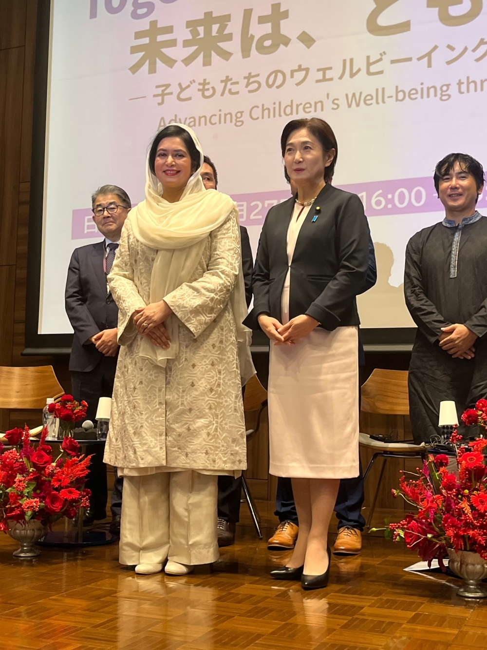 A two-shot of Parliamentary Vice-Minister IKUINA on stage and the spouse of Prime Minister Rahman of Bangladesh