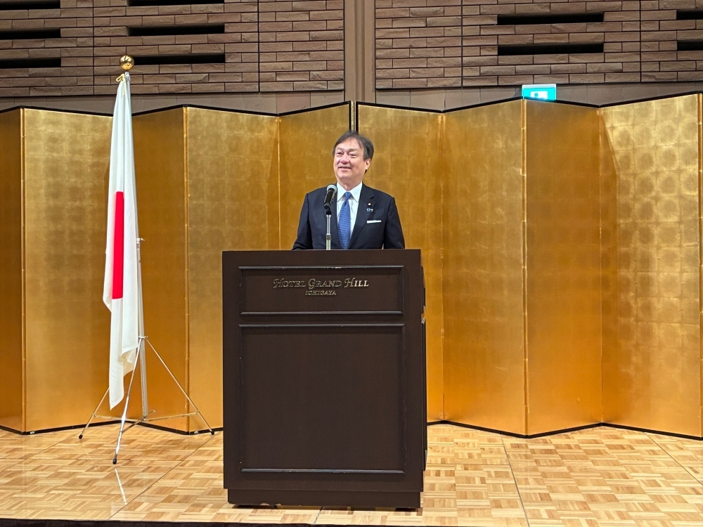 State Minister HORII delivering his opening speech in front of golden party screen