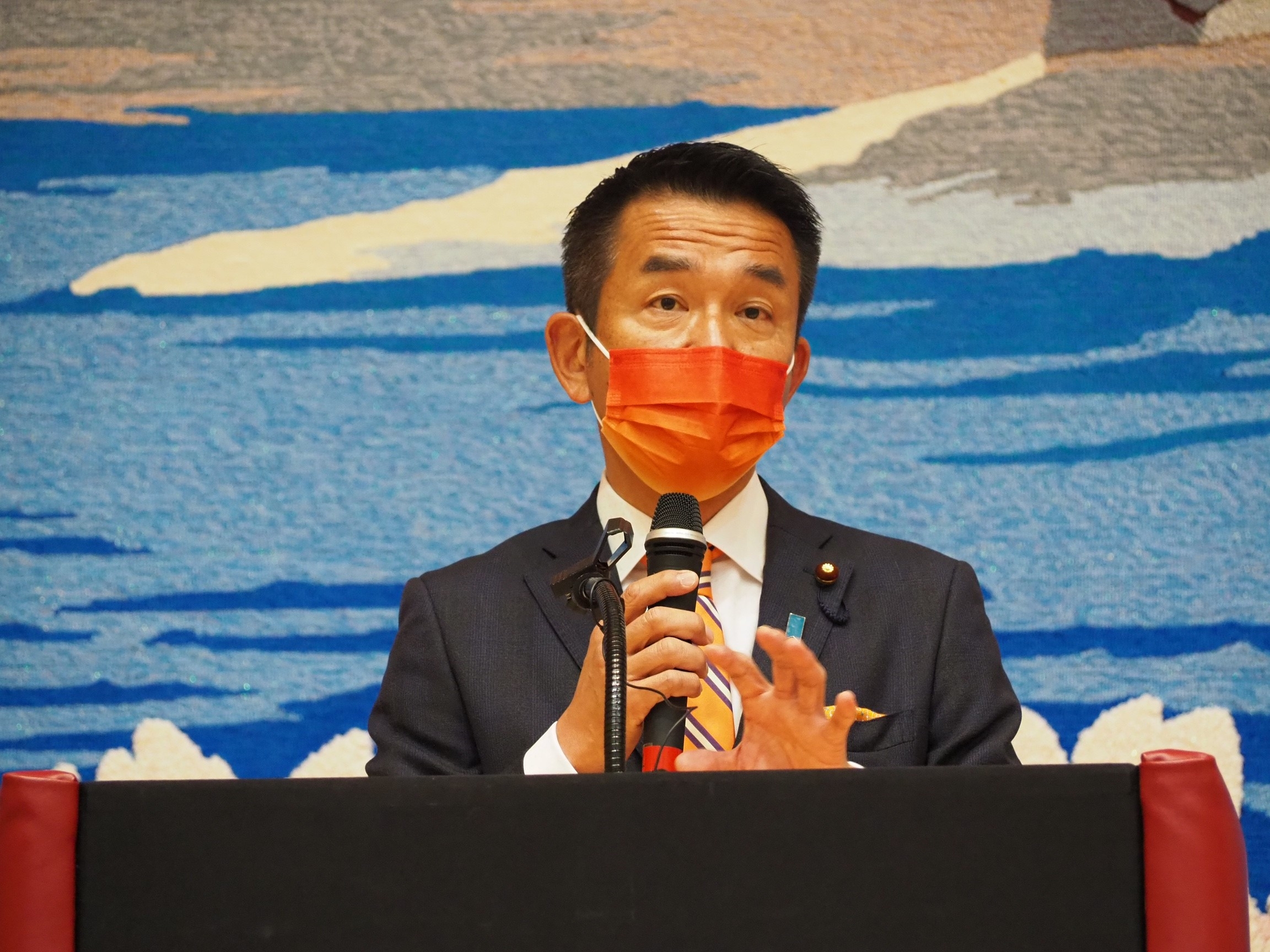 演壇に立ち、開会式で挨拶する、小田原副大臣の様子