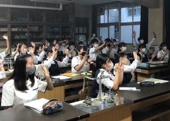(写真1)モニターを見て手を上げる愛媛県立松山東高等学校の生徒さんの様子