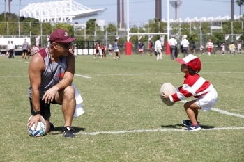 (写真1)ラグビー・チームの男性(左)とラグビーボールを両手で持つ子ども(右)