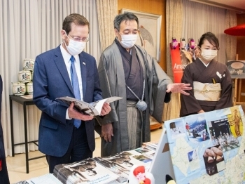 (写真3)パンフレットを読む大統領(左)と説明する水嶋大使(中央)